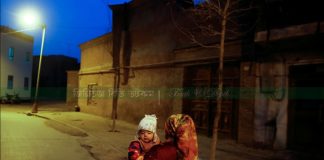 চিনের জিনজিয়াং উইঘুর স্বায়ত্তশাসিত অঞ্চল কাশগড়ের পুরানো শহরে রাতে এক নারী একটি শিশুকে নিয়ে যাচ্ছেন