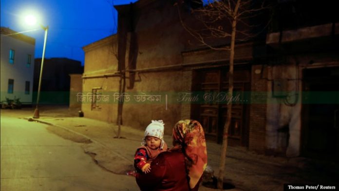 চিনের জিনজিয়াং উইঘুর স্বায়ত্তশাসিত অঞ্চল কাশগড়ের পুরানো শহরে রাতে এক নারী একটি শিশুকে নিয়ে যাচ্ছেন